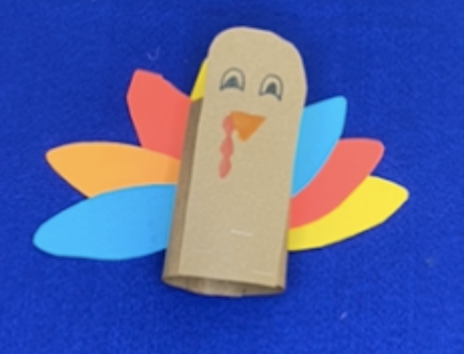 Brown paper turkey with red, orange, yellow, and blue feathers on a blue background.